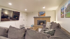 A living room with a fireplace, a large flat-screen TV, and a sofa. - Hot Tub, Pool Table, Fireplace, Sunny Patio (Arvada)