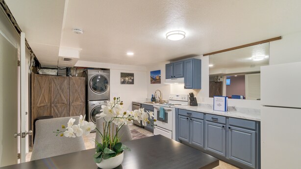 A modern kitchen with a dining area, a washing machine, and a large mirror above the counter. - Hot Tub, Pool Table, Fireplace, Sunny Patio (Arvada)