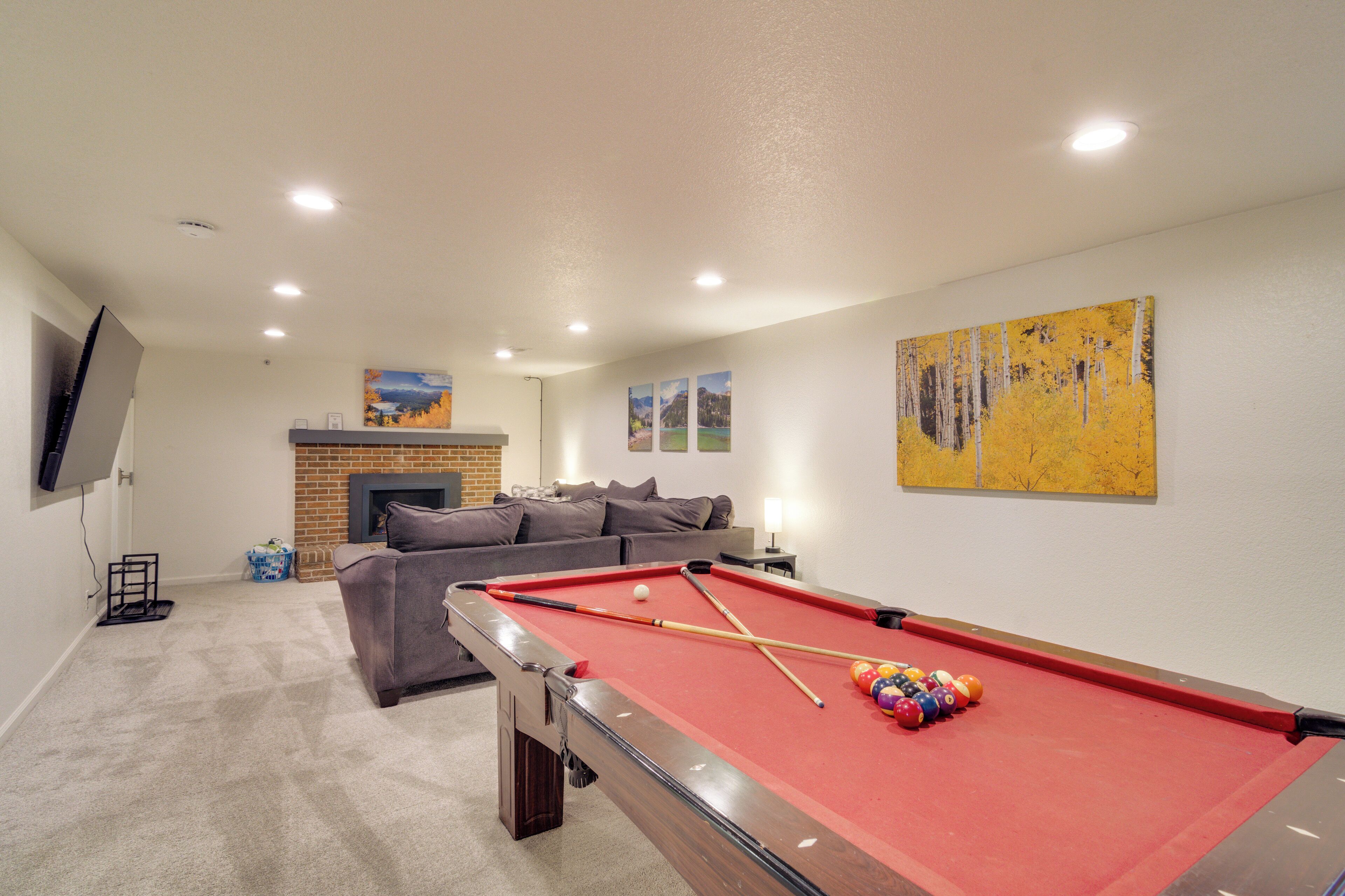 A pool table with balls, a sofa, a fireplace, and artwork on the walls.