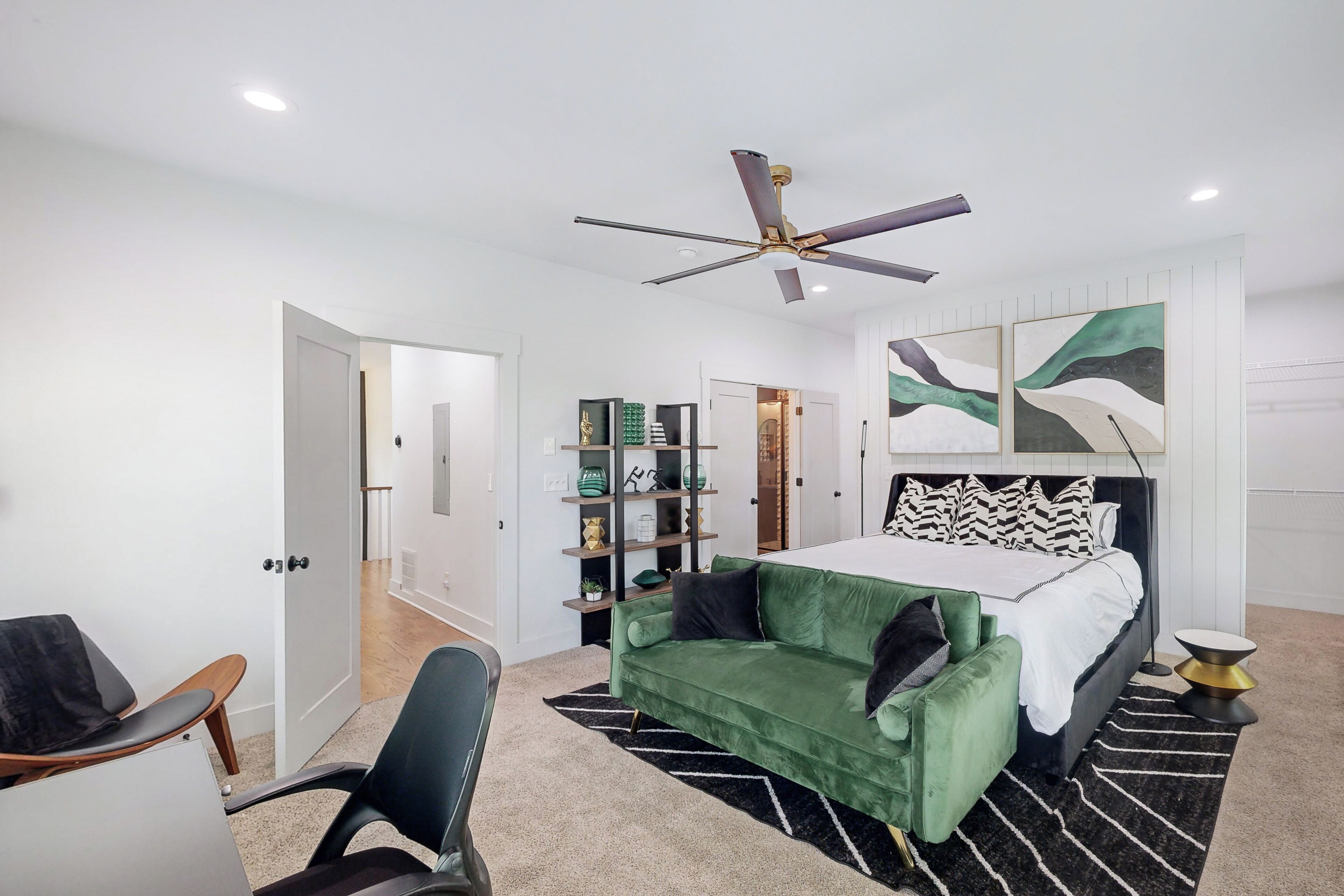 Une chambre moderne avec un lit, un canapé vert, un bureau et un ventilateur de plafond.