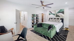 A modern bedroom with a bed, a green sofa, a desk, and a ceiling fan. - Atlanta Townhome: Walk to Mercedes-benz Stadium! (Atlanta)