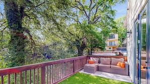 A balcony with a wooden railing, a grassy area, and a seating arrangement with cushions. - Atlanta Townhome: Walk to Mercedes-benz Stadium! (Atlanta)