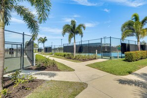 A fenced outdoor area with a pool, palm trees, and a clear sky. - New Home in Veranda Village w/ Resort Amenities! (Estero)