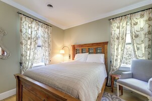 Un dormitorio con cama de madera, una mesita de noche, una lámpara, una silla y una ventana con cortinas.