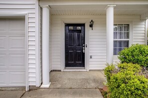 A house with a black front door, white columns, a garage door, and a window with curtains. - Great for Military Families! Quiet Columbia Home (Blythewood)