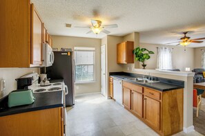 A kitchen with wooden cabinets, a stove, a microwave, and a ceiling fan. - Great for Military Families! Quiet Columbia Home (Blythewood)
