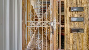 A wooden door with a metal gate, a wooden wall with a shelf, and a metal handle.
