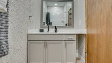 A bathroom with a white sink, a mirror, and a wooden door.