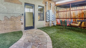 A patio with stone steps, a door, and a seating area with chairs.