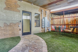 Un patio con escalones de piedra, una puerta y una zona de estar con sillas.