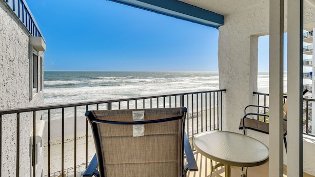 A balcony with a view of the ocean, a chair, and a small table. - Pool Access! Oceanfront Daytona Beach Shores Gem (Daytona Beach Shores)