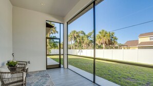 A modern room with large windows, a wooden floor, and a view of a grassy yard with trees. - 3 Mi to Manasota Beach! Sleek Home w/ Lanai (Venice)