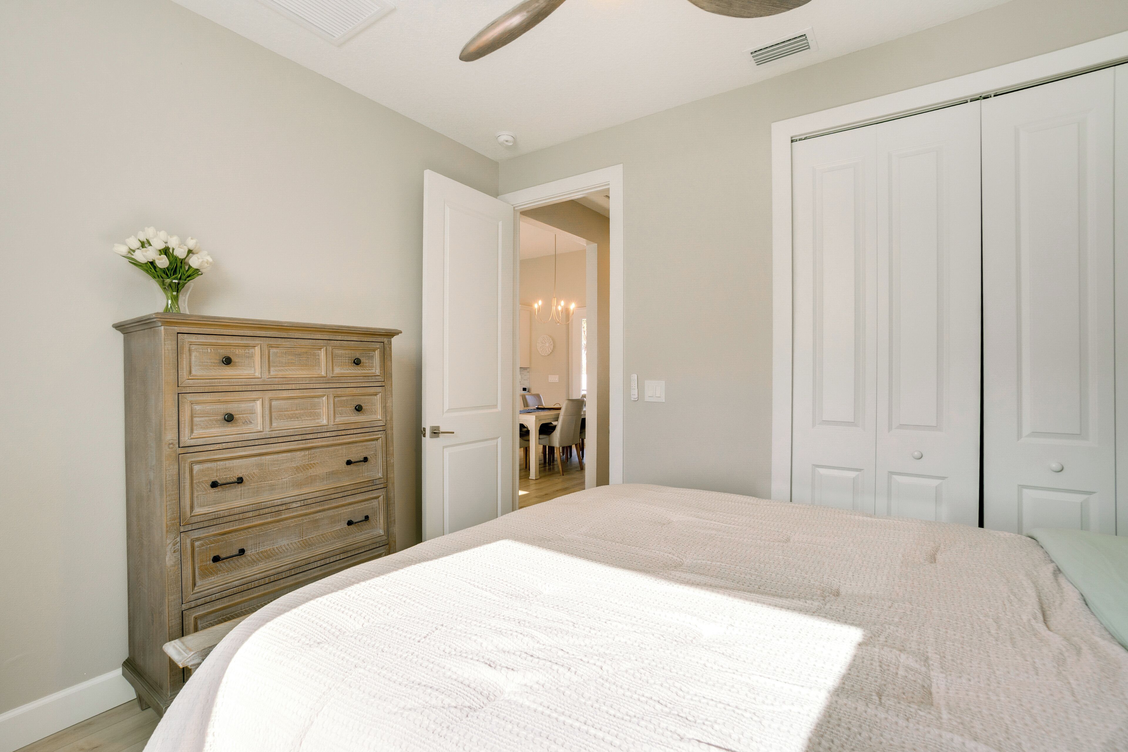 Une chambre à coucher comprenant un lit, une commode et une porte donnant sur une autre pièce.