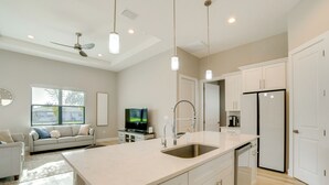 A modern kitchen with a central island, white cabinetry, and a built-in dishwasher. - 3 Mi to Manasota Beach! Sleek Home w/ Lanai (Venice)