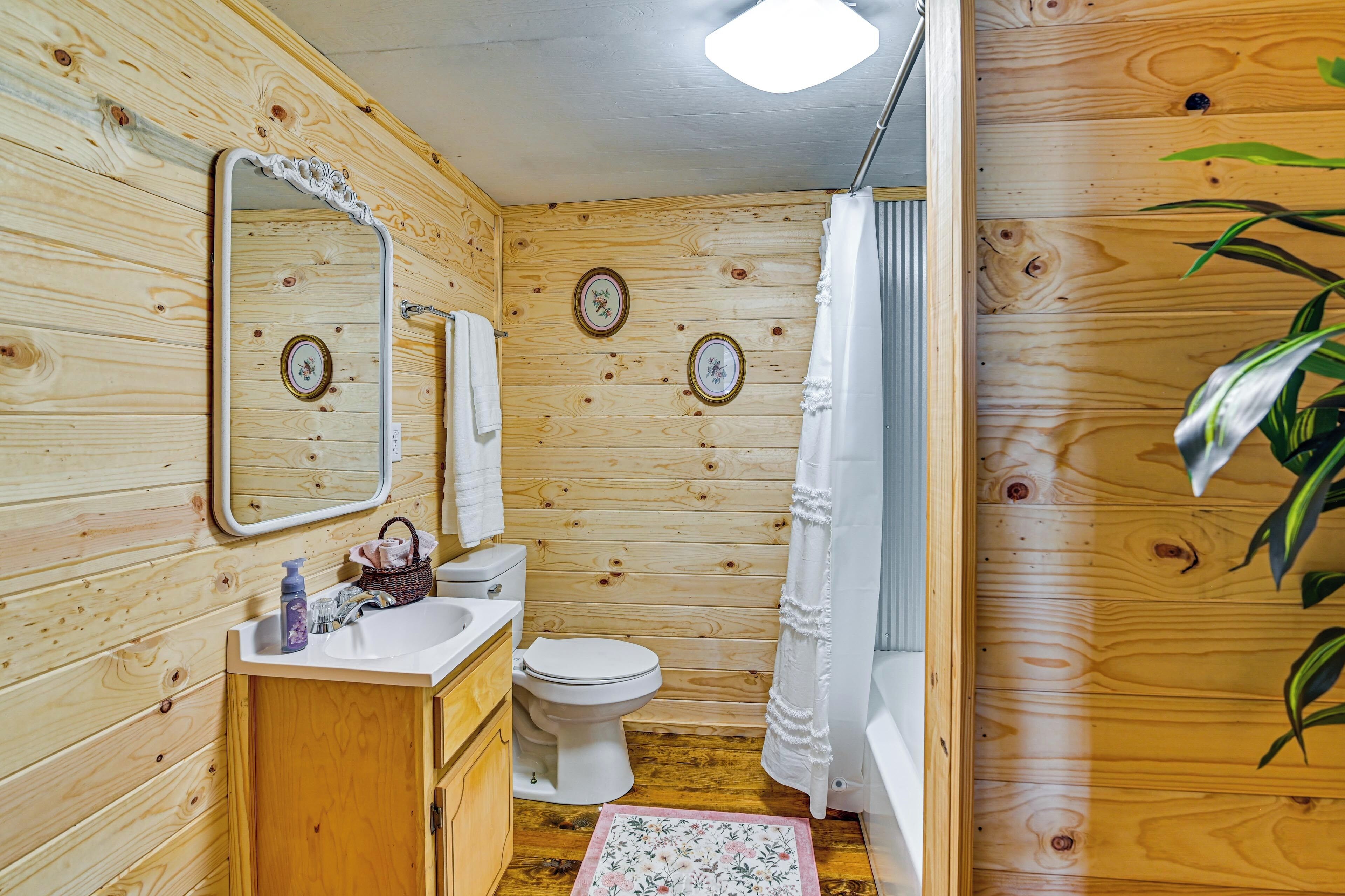 A wooden cabin bathroom with a sink, toilet, and mirror.