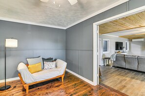 A room with a wooden floor, grey walls, a sofa with cushions, a floor lamp, and a partially visible adjacent room. - Surrounding Pasture Views! Peaceful Escape in Iuka (Iuka)