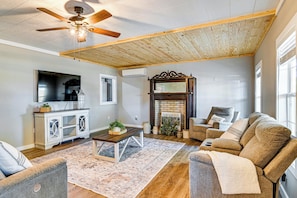 A living room with a ceiling fan, a fireplace, a sofa, a coffee table, and a television. - Surrounding Pasture Views! Peaceful Escape in Iuka (Iuka)