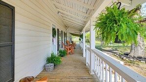 Eine überdachte Veranda mit Holzboden, weißen Geländern und Sitzmöbeln.
