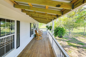 A covered porch with a wooden floor, white walls, and a view of a grassy yard. - Surrounding Pasture Views! Peaceful Escape in Iuka (Iuka)