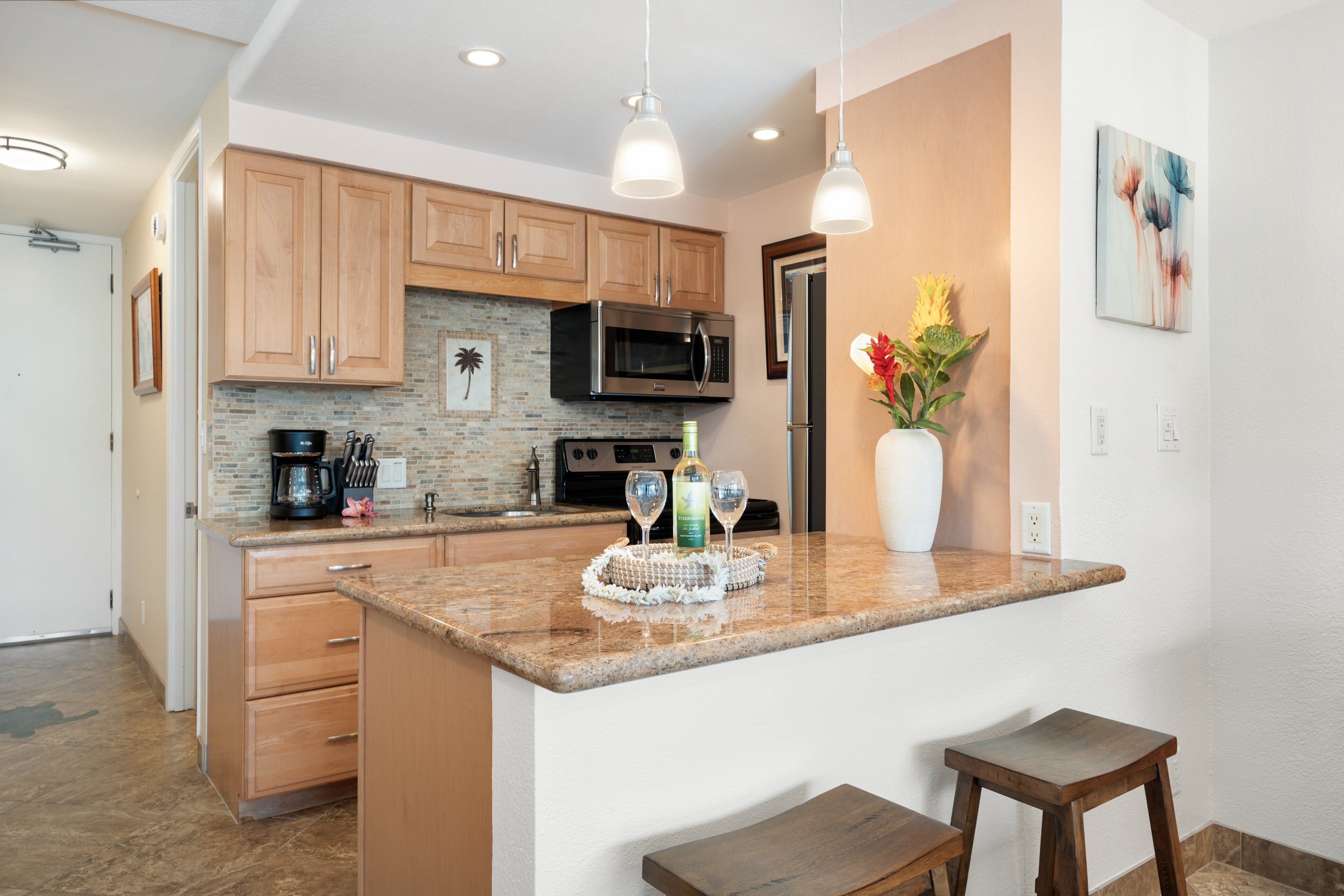 A kitchen with wooden cabinets, a microwave, a refrigerator, and a granite countertop.