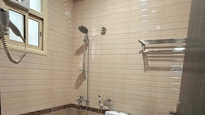 Un baño con bañera, inodoro y lavamanos, paredes de azulejos y ventana.