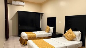 Una habitación de hotel con dos camas, un armario, una mesita de noche y un aire acondicionado.