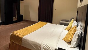 Una habitación de hotel con una cama grande, una mesita de noche, un armario y una lámpara en el techo.