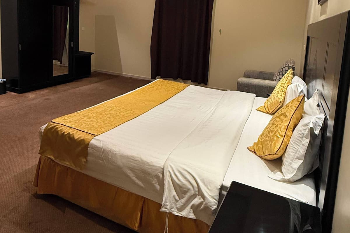 A hotel room with a large bed, a bedside table, a wardrobe, and a ceiling light.