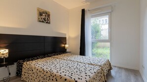 A bedroom with a bed, bedside lamps, a window, and a painting on the wall. - Cozy apartment for 4 people with a terrace (Grasse)