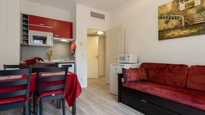 A compact living space with a kitchenette, a dining area with chairs, a sofa, and a painting on the wall. - Cozy apartment for 4 people with a terrace (Grasse)