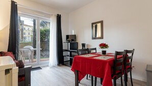 A dining area with a red tablecloth, chairs, a small potted plant, and a television on a stand. - Cozy apartment for 4 people with a terrace (Grasse)