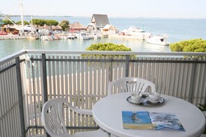 Ein Balkon mit Tisch, Stühlen und Blick auf eine Marina mit Booten und Gebäuden.