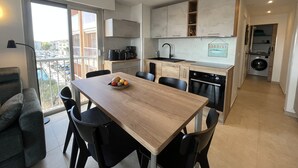 Una cocina moderna con comedor, lavadora y vista a la ciudad.