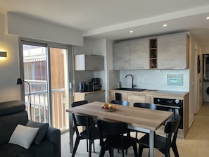 A modern kitchen with a dining area, a sofa, and a view of the outside. - Incredible sea view, 2-bedroom apartment with sleeping alcove for 4 lucky guests, air conditioning, large garage, beach 50 meters away, everything within walking distance (Fréjus)