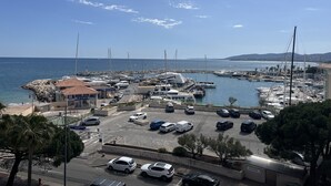 Un puerto deportivo con barcos amarrados, una zona de estacionamiento con automóviles y un edificio con señalización.