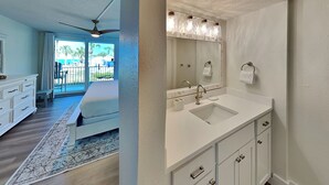 Une salle de bain moderne avec un grand miroir, un lavabo blanc et un ventilateur de plafond.