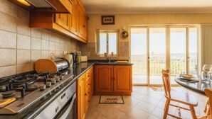 Eine Küche mit Holzausstattung, einem Gasherd und Blick auf die Stadt durch große Fenster.
