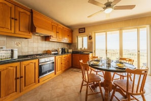 Una cucina con mobili in legno, un fornello e un'area pranzo con tavolo e sedie.