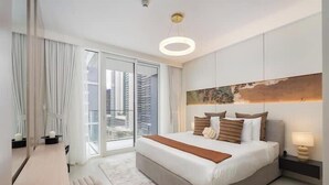 Un dormitorio moderno con una cama grande, vistas a edificios altos y una lámpara de techo circular.