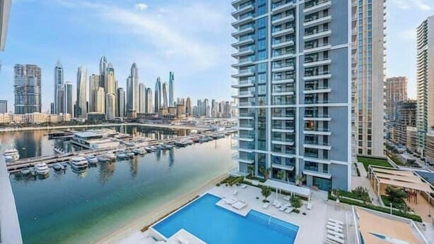 Un edificio de gran altura con piscina en la azotea y acceso a un puerto deportivo.