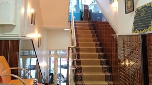 A hotel lobby with a reception desk, a staircase, and a view of the street. - Ari Otel (Erzurum)
