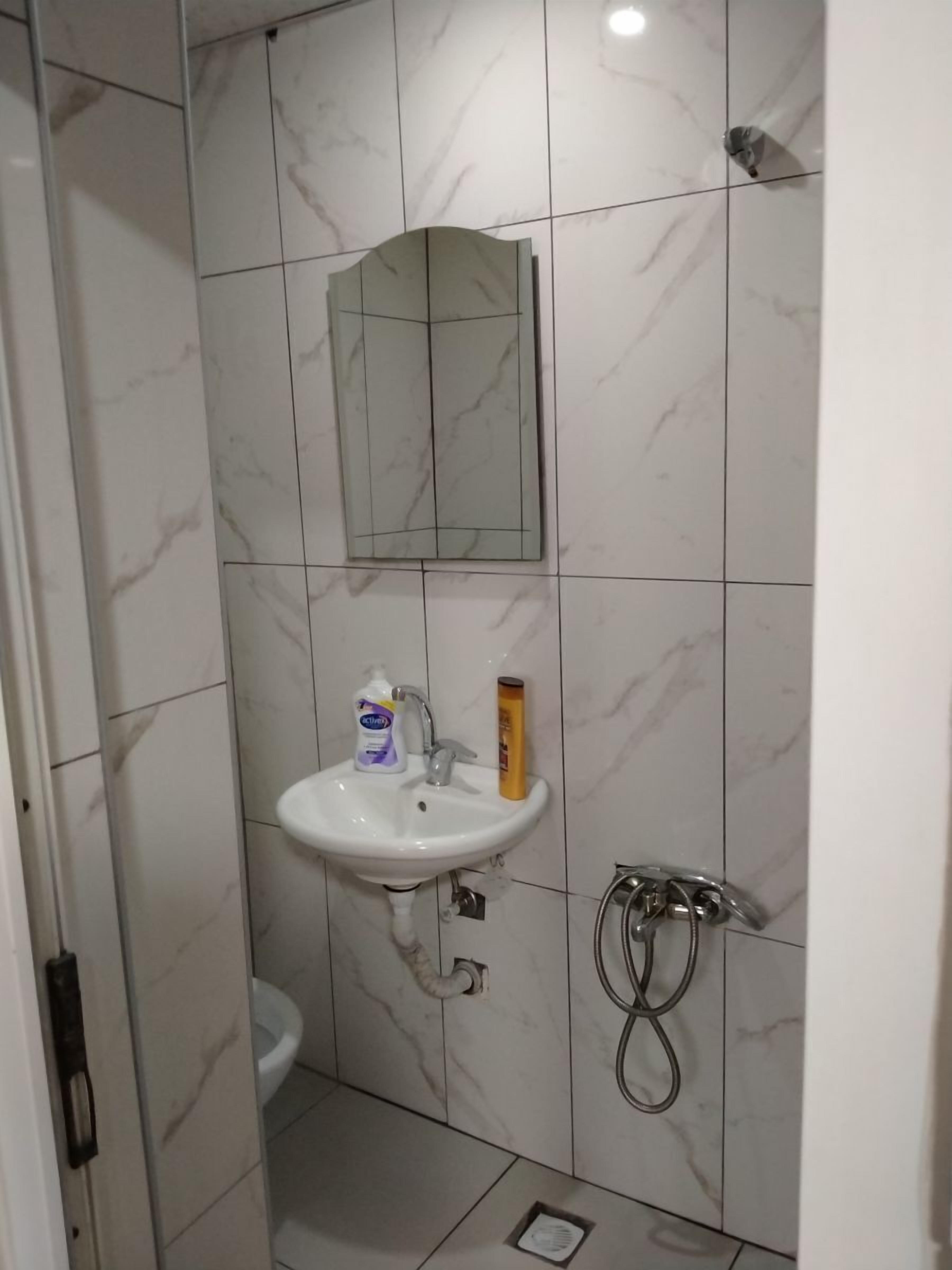 Baño con lavamanos blanco, espejo y ducha.