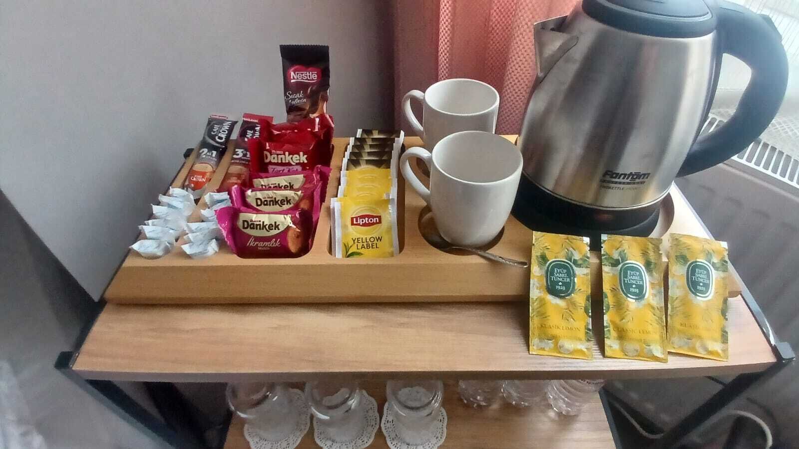 Ein Tablett mit Kaffeekapseln, einem Wasserkocher und Tassen auf einem Holztisch.