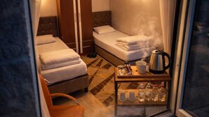 A hotel room with two beds, a wardrobe, a coffee table with a kettle, and a window with curtains. - Ari Otel (Erzurum)