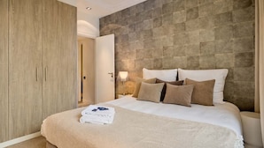 Un dormitorio con cama, armario y pared con textura de piedra.