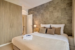 A bedroom with a bed, a wardrobe, and a stone-textured wall. - Superb 2 bdr Apartment Terrace Neuilly-sur-seine (Neuilly-sur-Seine)