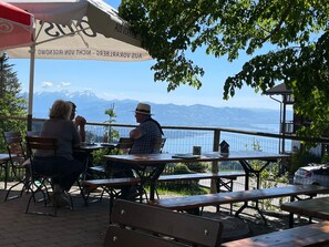 An outdoor seating area with tables and benches, overlooking a body of water and mountains. - Apartment "Krokus" with Mountain View, Balcony, and Wi-Fi (Weiler-Simmerberg)