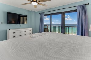 A bedroom with a large bed, a ceiling fan, a TV, and a view of the ocean. - Wrap around Views! Newly Remodeled 9th Floor 3BR 3BA Commodore *BEACH CHAIRS! (Panama City Beach)