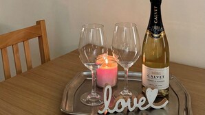 Una mesa de comedor con una bandeja que contiene una botella de vino, copas y una vela.