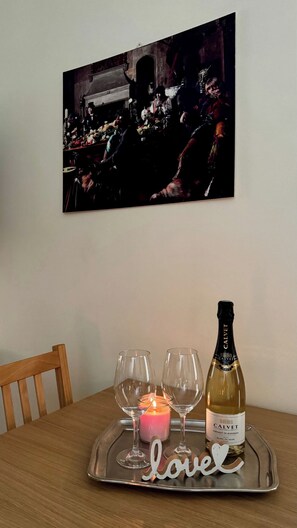 A dining table with a tray holding a bottle of wine, glasses, and a candle. - Charming Apartment with Wood Fireplace, Garden & Mountain View near Oropa (Biella)